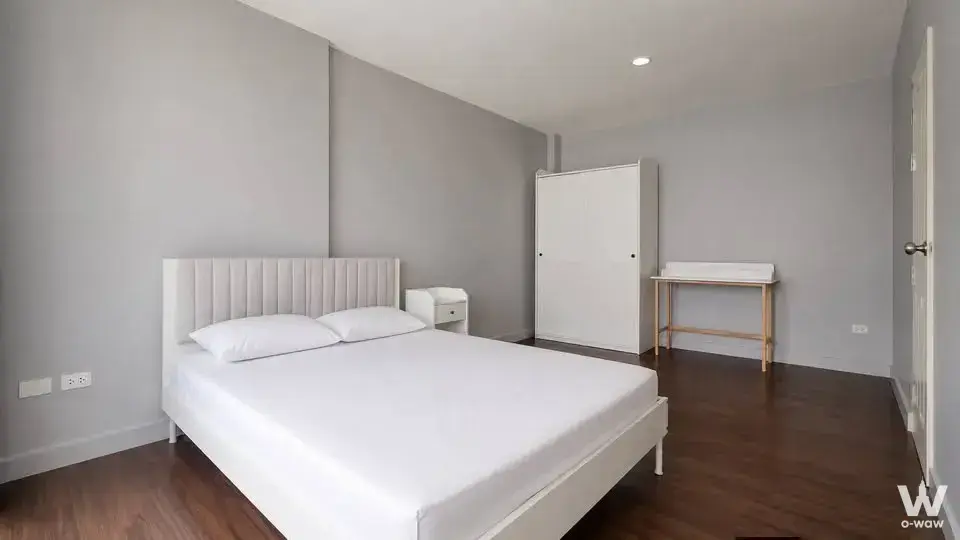 Modern minimalist master bedroom with white tufted headboard and light wood desk in Town Avenue Srinagarindra