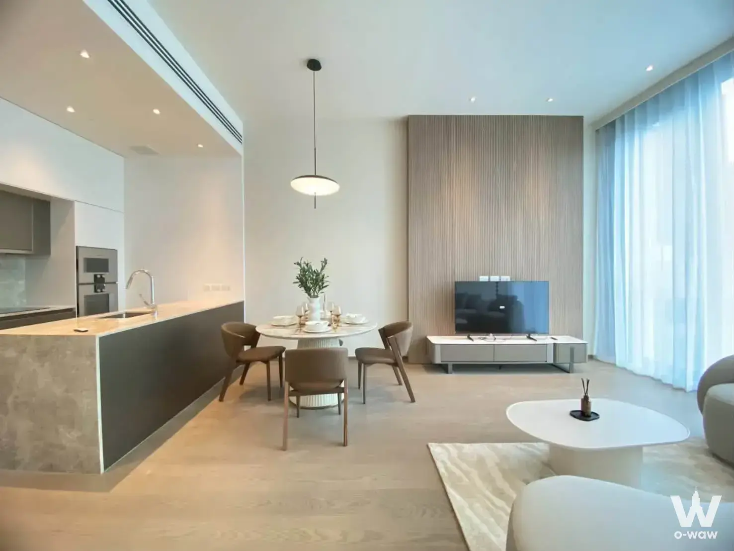 Open-plan living area in SCOPE Langsuan with a marble dining table and modern kitchen island