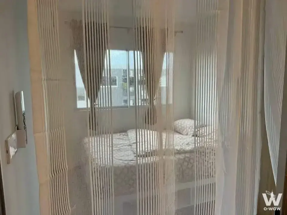 1-bed condo for rent in Sena Kith Srinakarin-Sridan featuring a bedroom with a queen bed and beaded curtain divider
