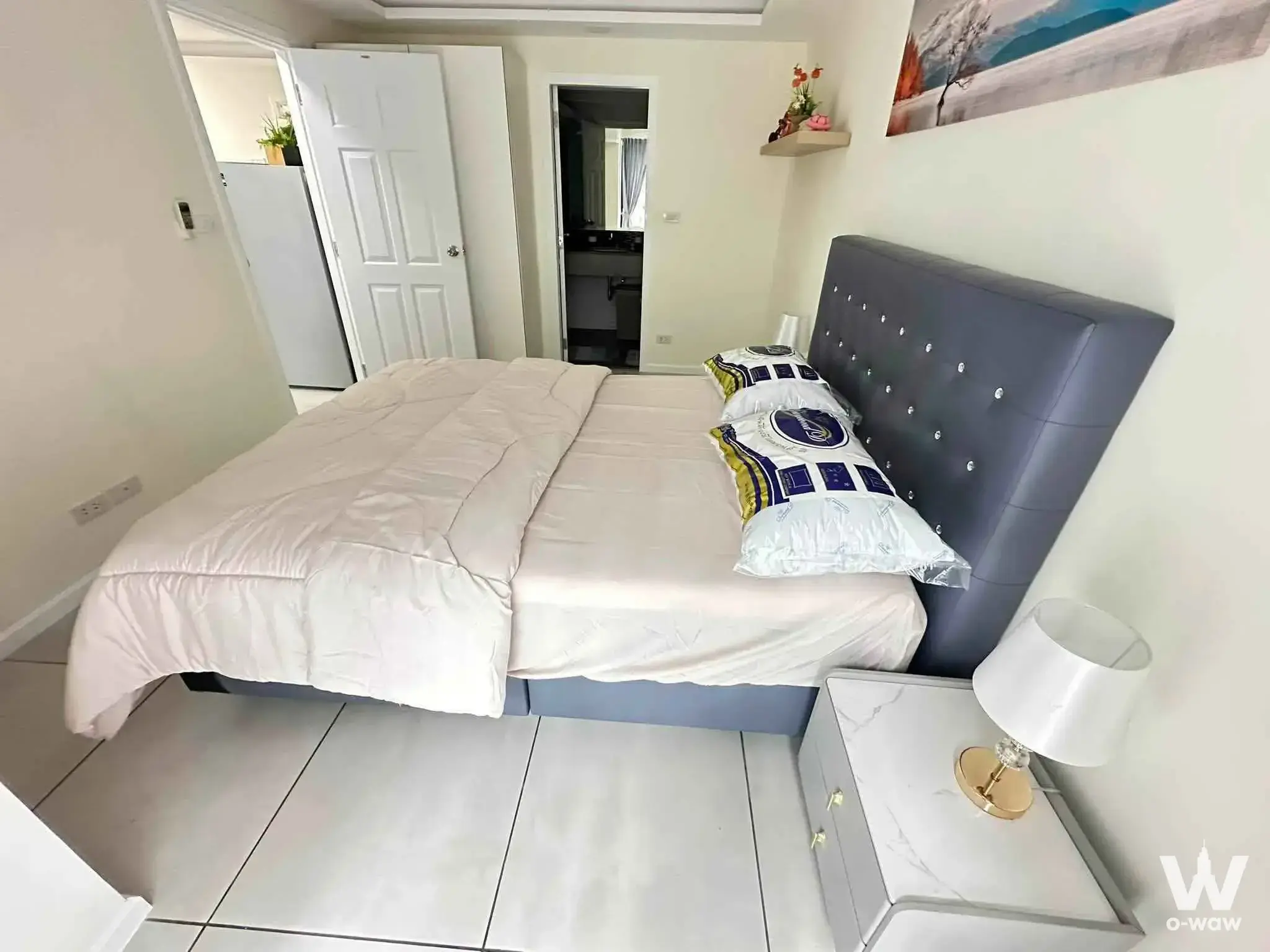 Queen bed with dark grey tufted headboard and marble nightstand in this Siam Oriental Tropical Garden condo bedroom
