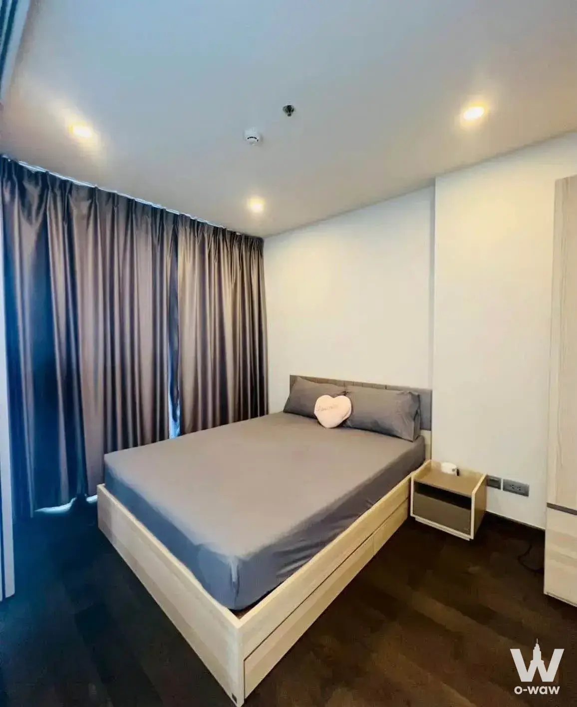 Light-wood platform bed with storage drawers and blackout curtains in Ideo Q Siam-Ratchathewi