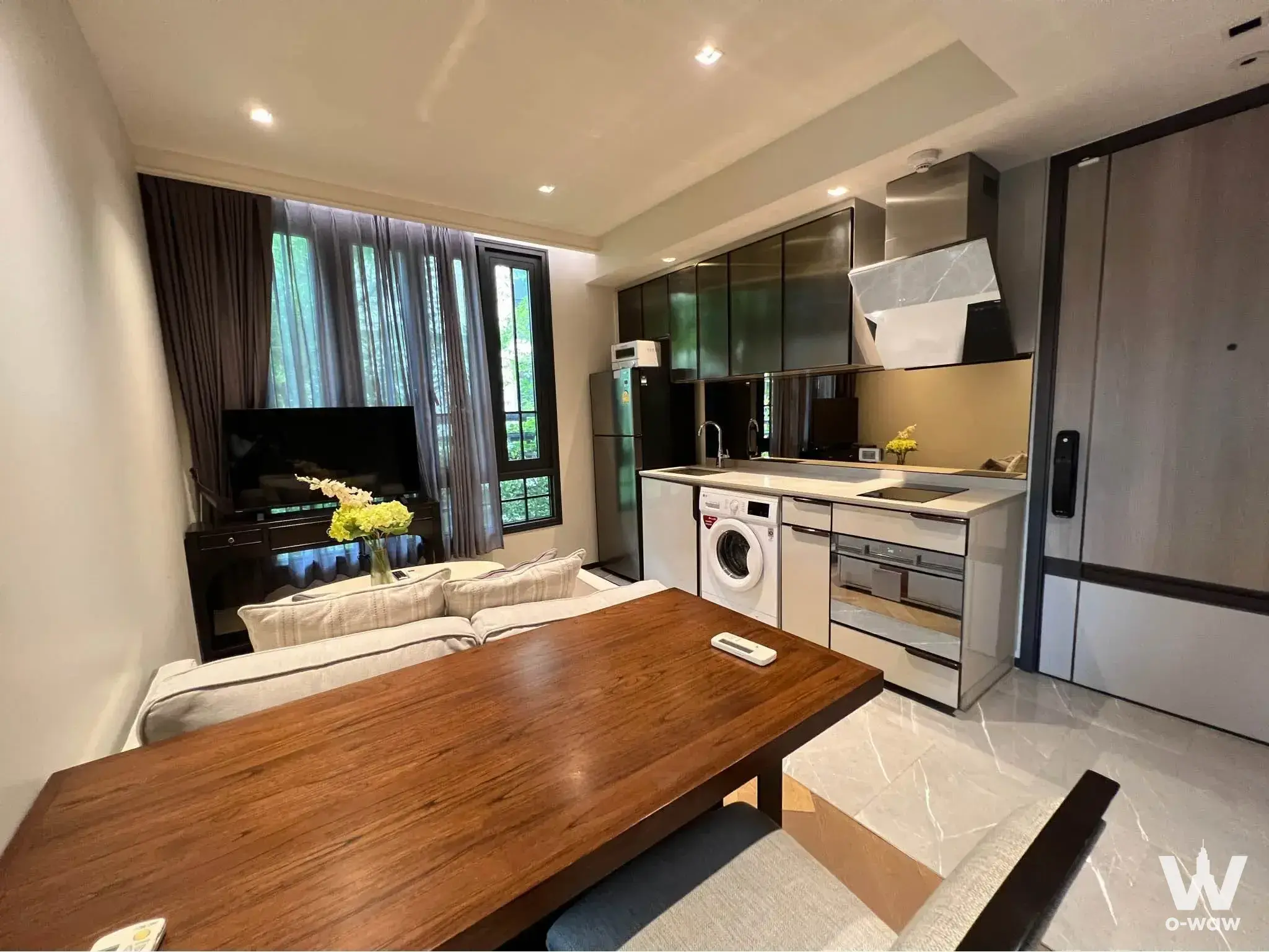 Open-plan living and kitchen in a 2-bed Sukhumvit 61 condo featuring walnut dining table and quartz island