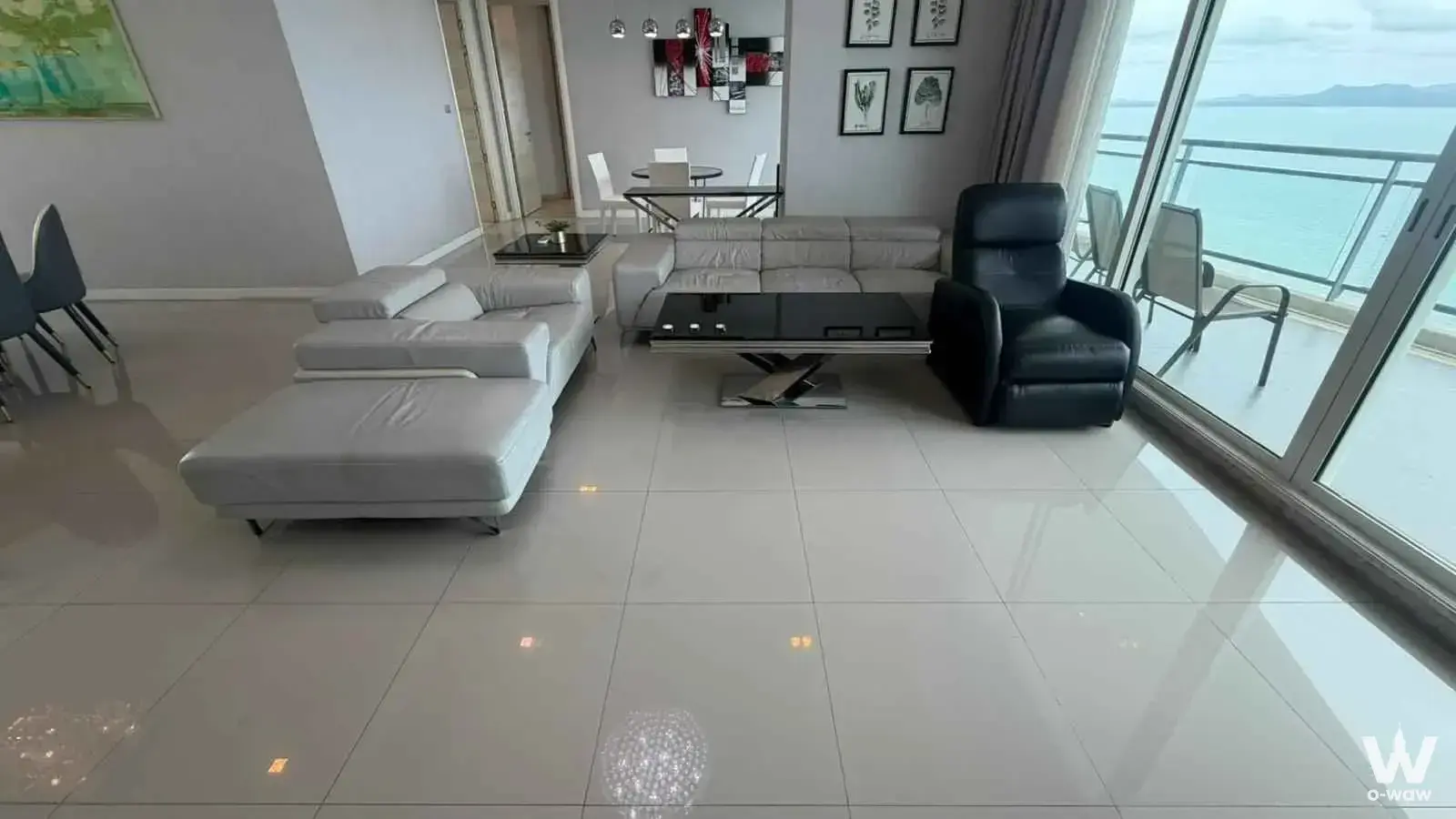 Spacious living room in a Reflection Jomtien Beach condo with grey leather sofa and sliding doors to an ocean view