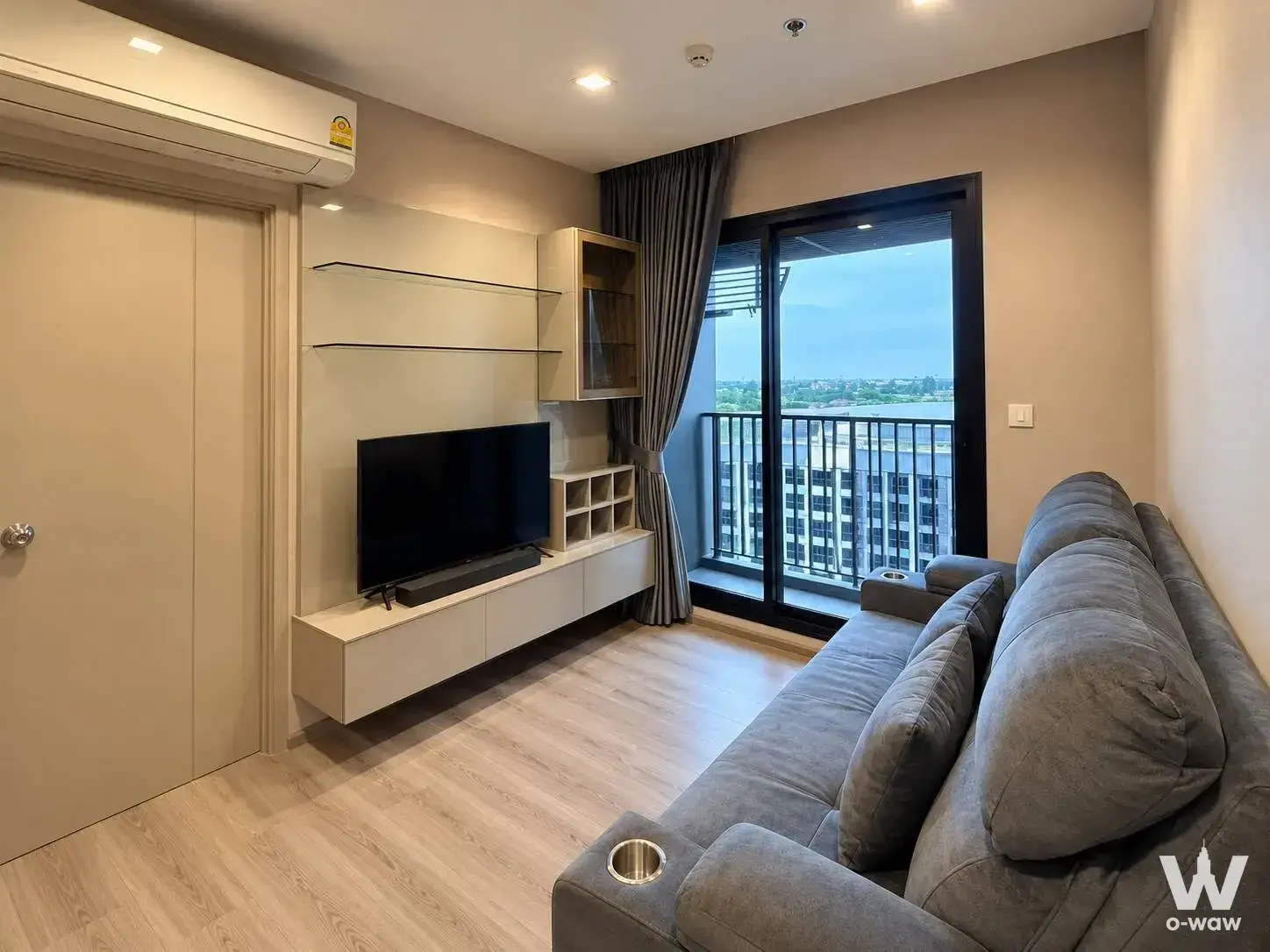 The Politan Rive living room with grey sectional sofa, river view, and floating media console