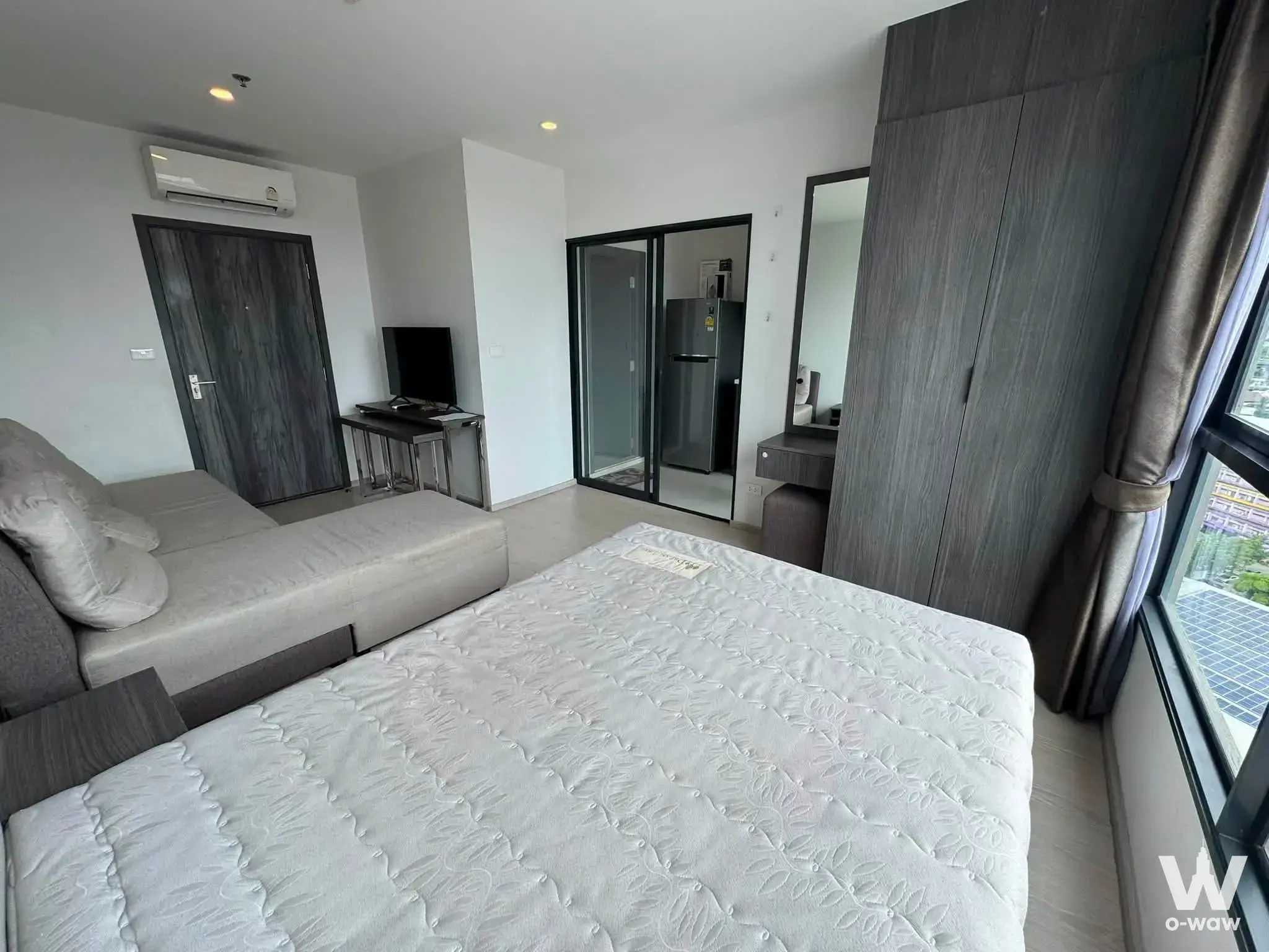 Furnished studio bedroom with queen bed, wardrobe, and city view in ELIO DEL NEST condo for rent