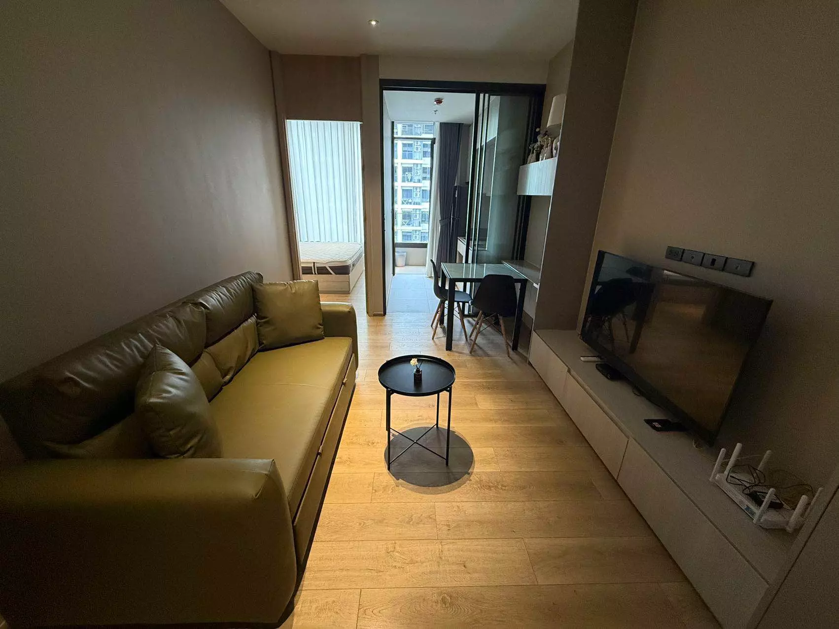 Olive-green sofa and floating TV console in a furnished The Fine Bangkok living room
