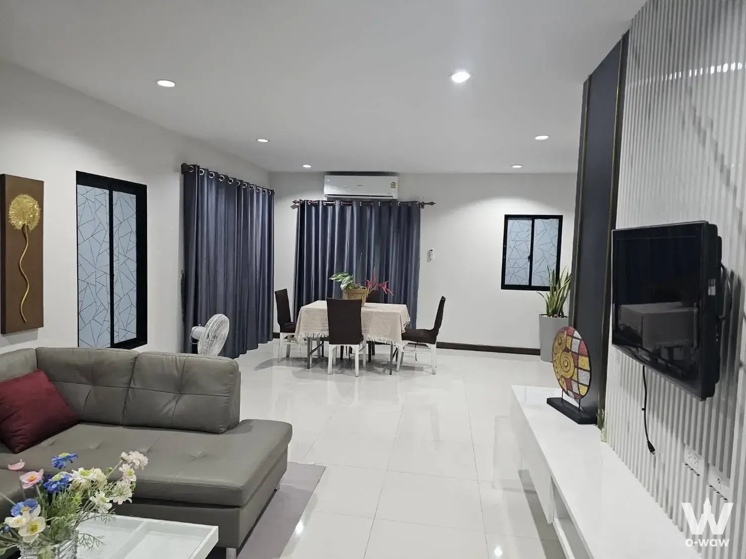 Open-plan living room in a 3-bed house for rent at The Plant Chaiyaphruek Wongwaen with grey sectional sofa and glass coffee