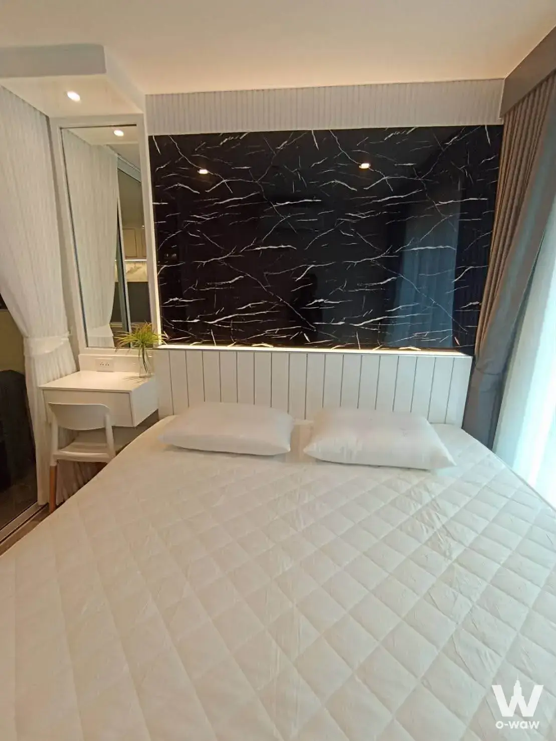 Queen bed with black marble feature wall and floating desk in this 1-bed condo for rent at Regent Home Bangna