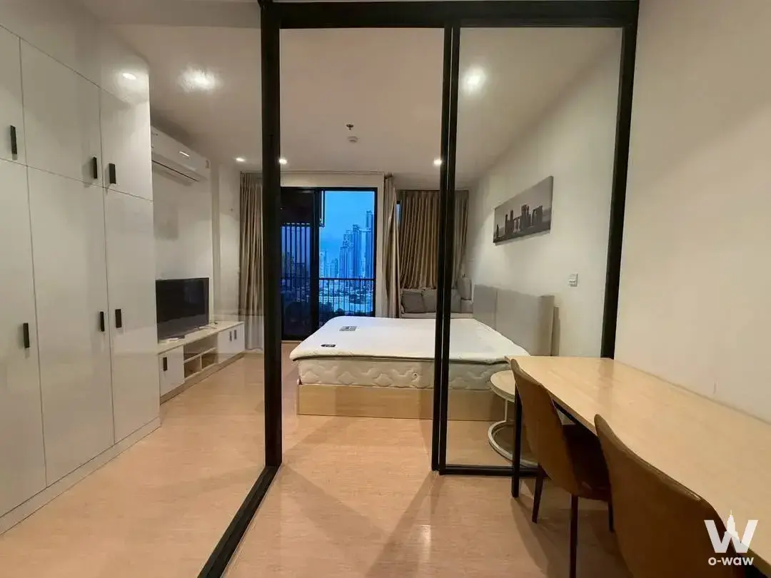 Open-plan studio with glass partition, dining set, and balcony view in a 1-bed condo for rent at MARU Ekkamai 2