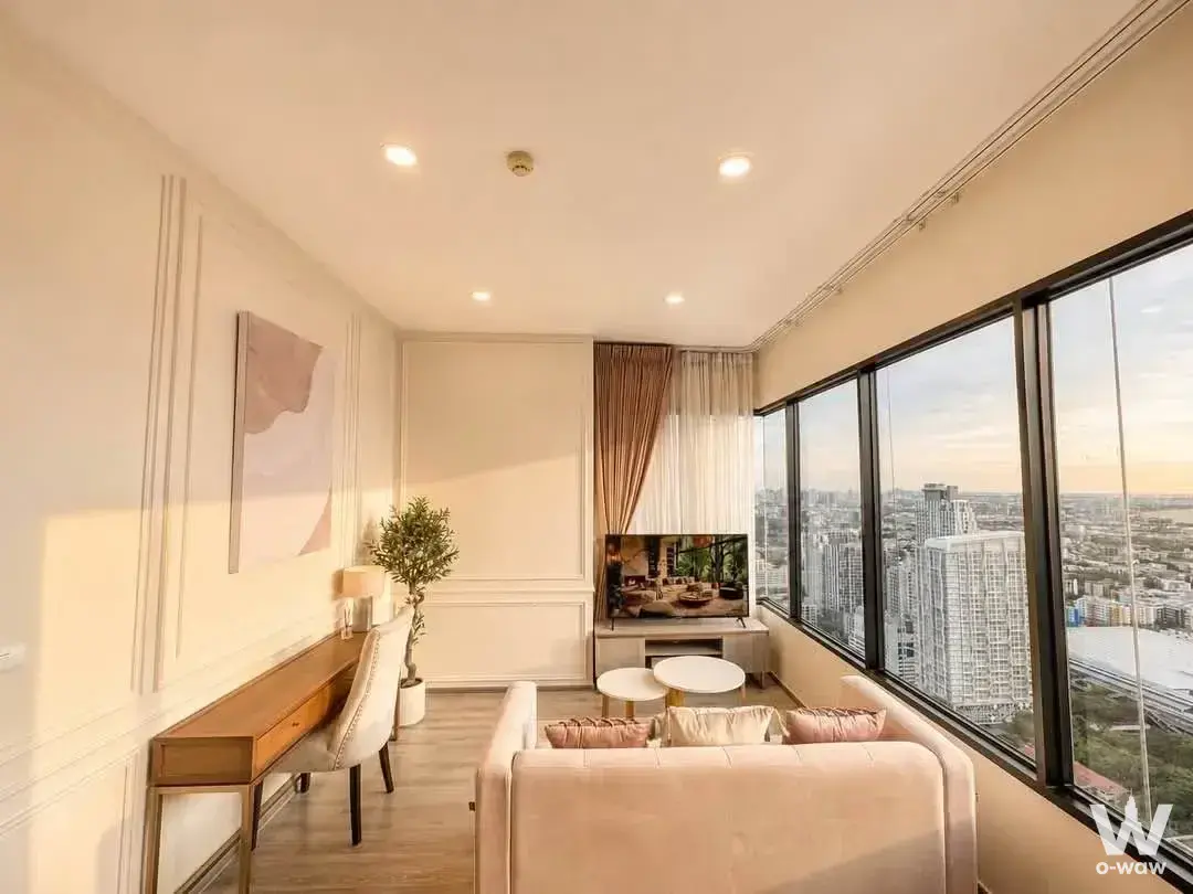 Cream sofa facing floor-to-ceiling windows with city views in a 2-bed rental at KnightsBridge Prime Onnut