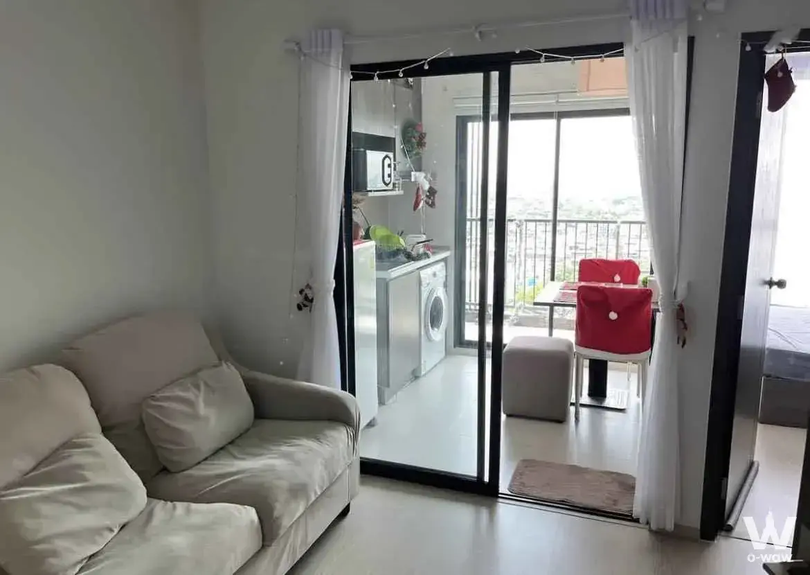 The bright living room in this one-bedroom ELIO DEL NEST condo has a cream sofa, glass partition and fairy lights