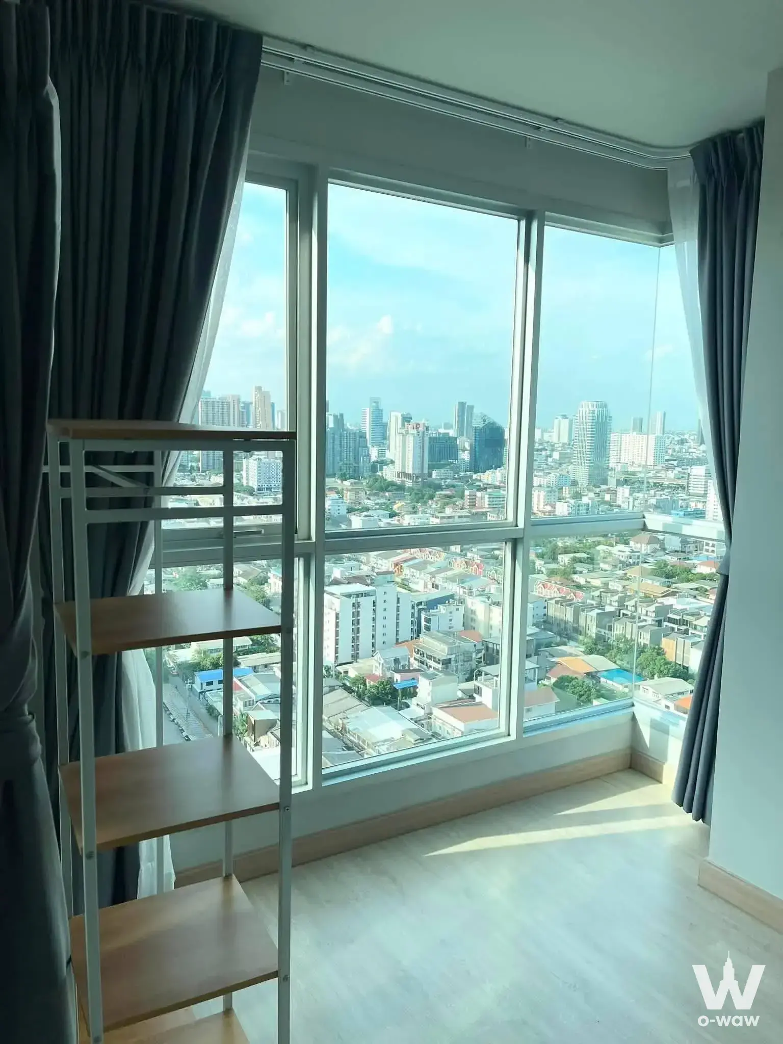 Floor-to-ceiling windows framing the city skyline in a bright Lumpini Selected Sutthisan 1-bed condo living room