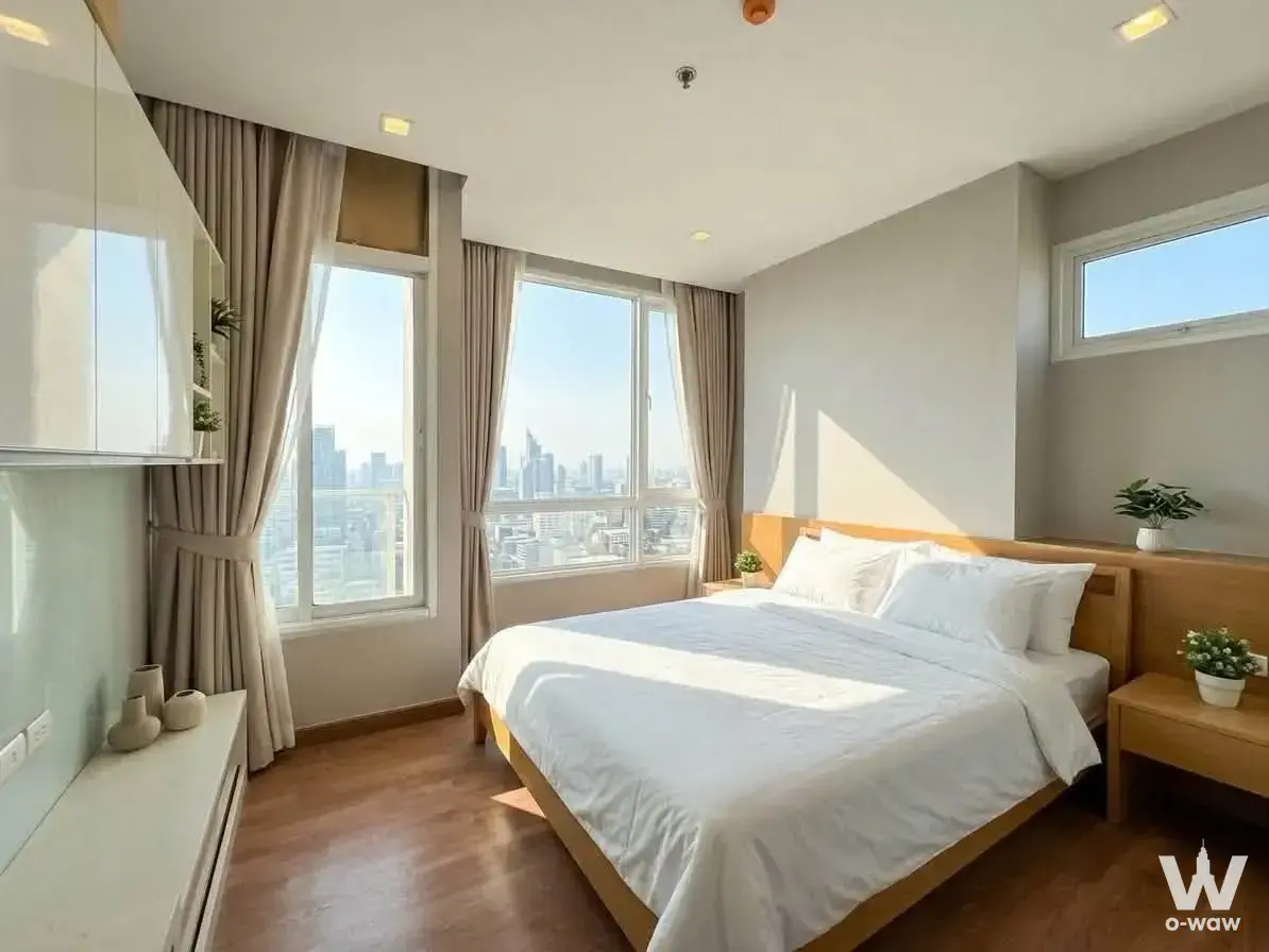1-bed condo for rent in The Coast Bangkok master bedroom with queen bed, oak nightstands, and high-rise city skyline view