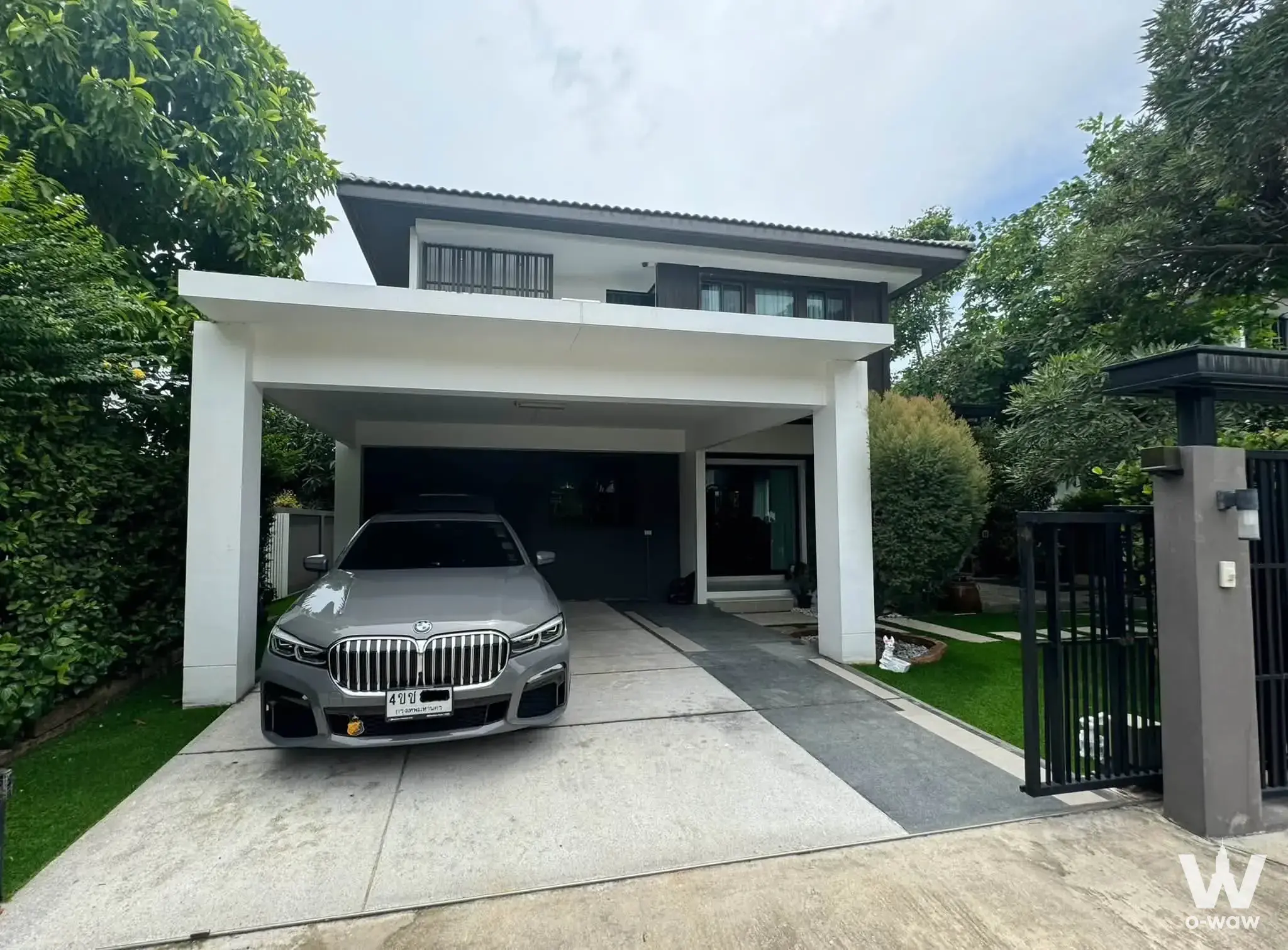 White two-story house exterior with carport and BMW sedan at this 4-bed Mantana Bangna Km.15 rental