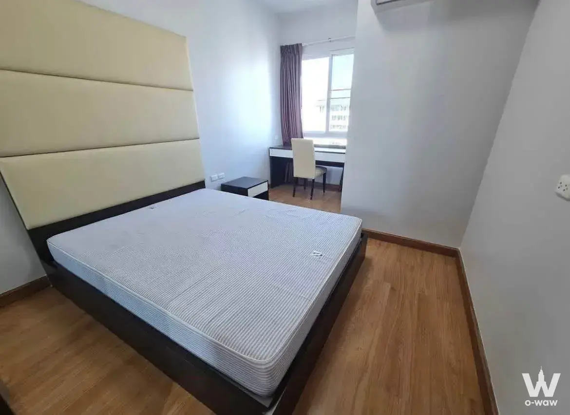 Modern bedroom in Supalai River Resort featuring a beige headboard and window desk