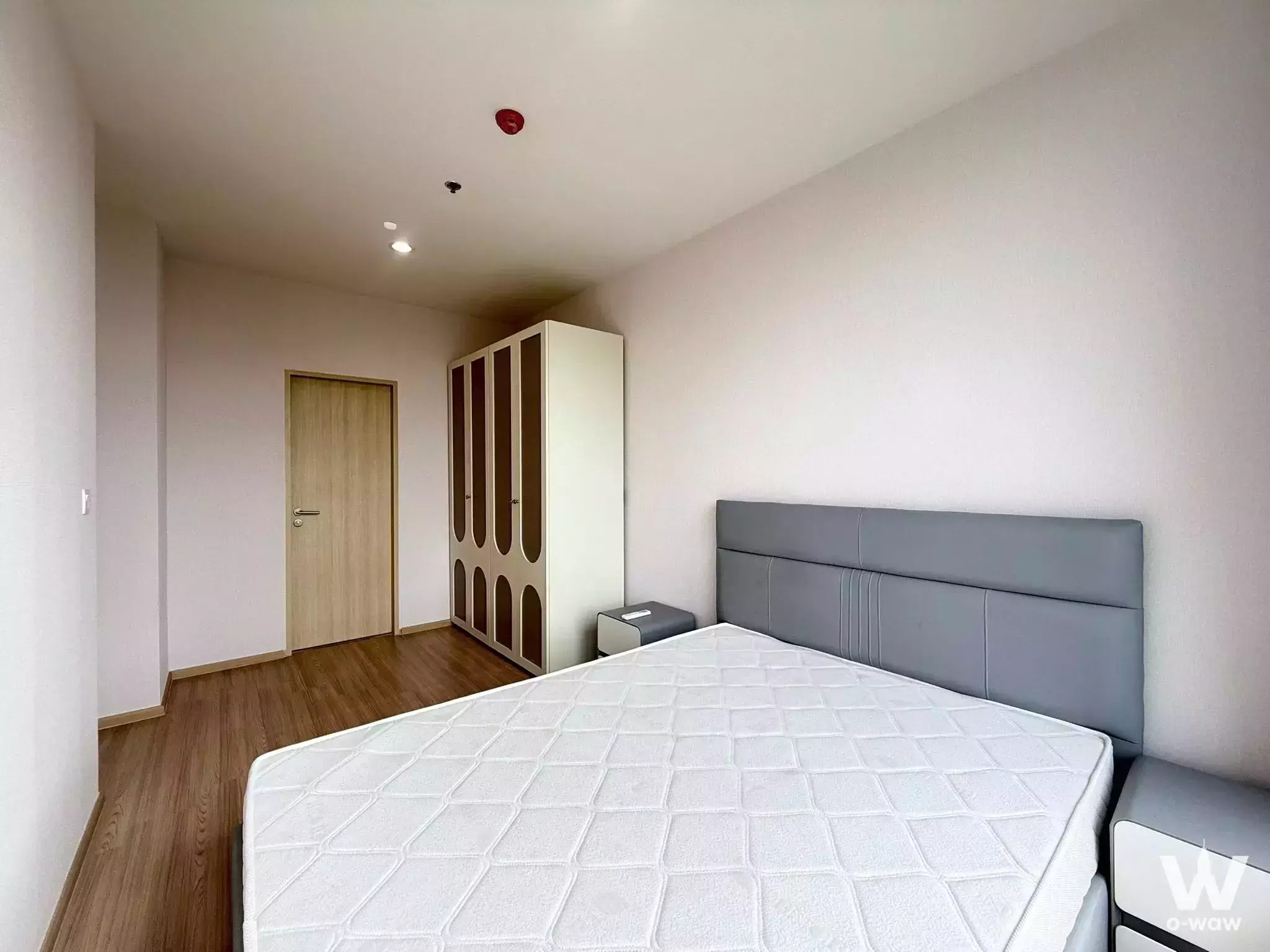 Skyrise Avenue Sukhumvit 64 bedroom includes a queen bed and tall wardrobe with arched inset door panels