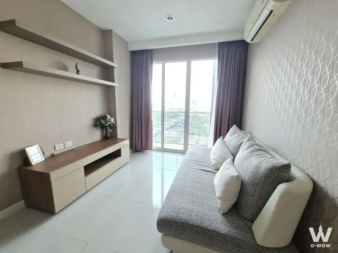Grey sofa and media console in a furnished living room of a 1-bed condo for sale at The Mark Ratchada