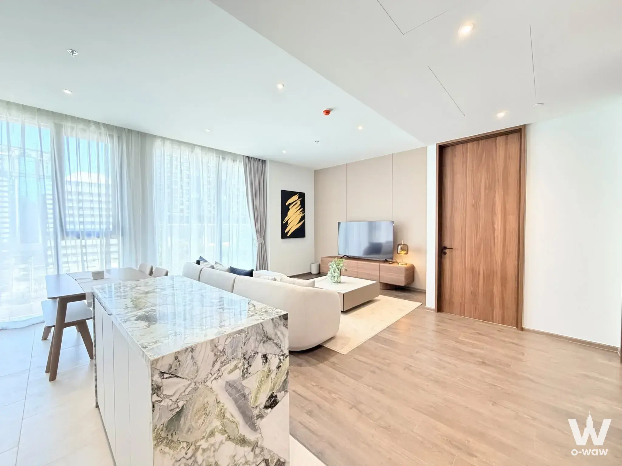 Open-plan living area in ROMM CONVENT with marble island, cream sofa, and floor-to-ceiling city views