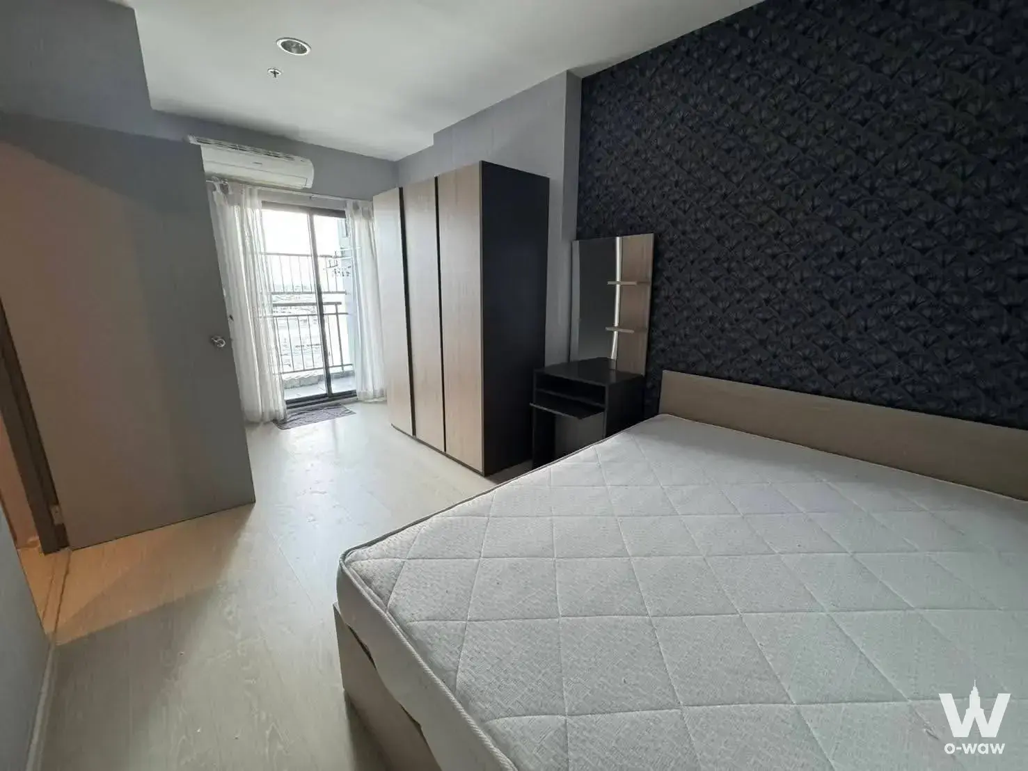 Bedroom in an IDEO Sukhumvit 115 unit with geometric wallpaper accent wall and built-in sliding wardrobe