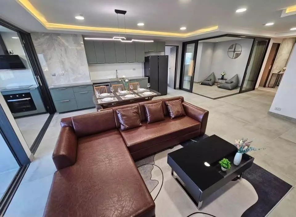 Modern 3-bed condo living area in Diamond Sukhumvit with brown leather sofa and sage-green kitchen
