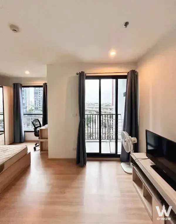 1-bed condo for rent in THE BASE Rama 9-Ramkhamhaeng featuring an open plan layout, balcony access, and minimalist furniture