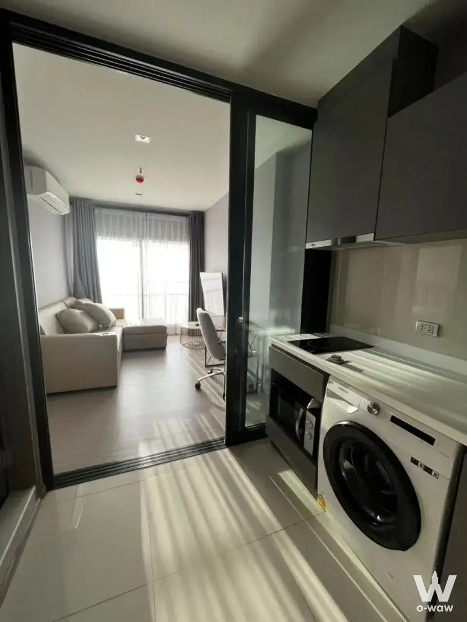 Open-plan 1-bed condo in Life Asoke Hype with cream sofa and modern kitchenette