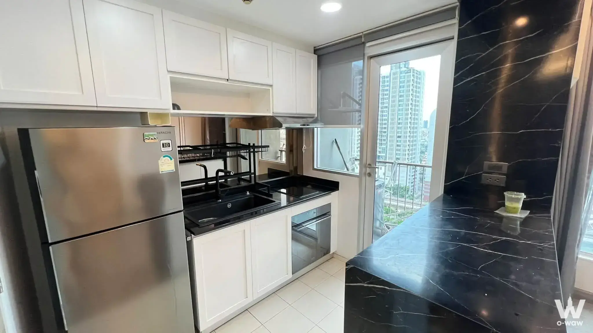Black marble island and stainless steel appliances in a modern kitchen of a 2-bed condo for rent at Hive Taksin Condominium