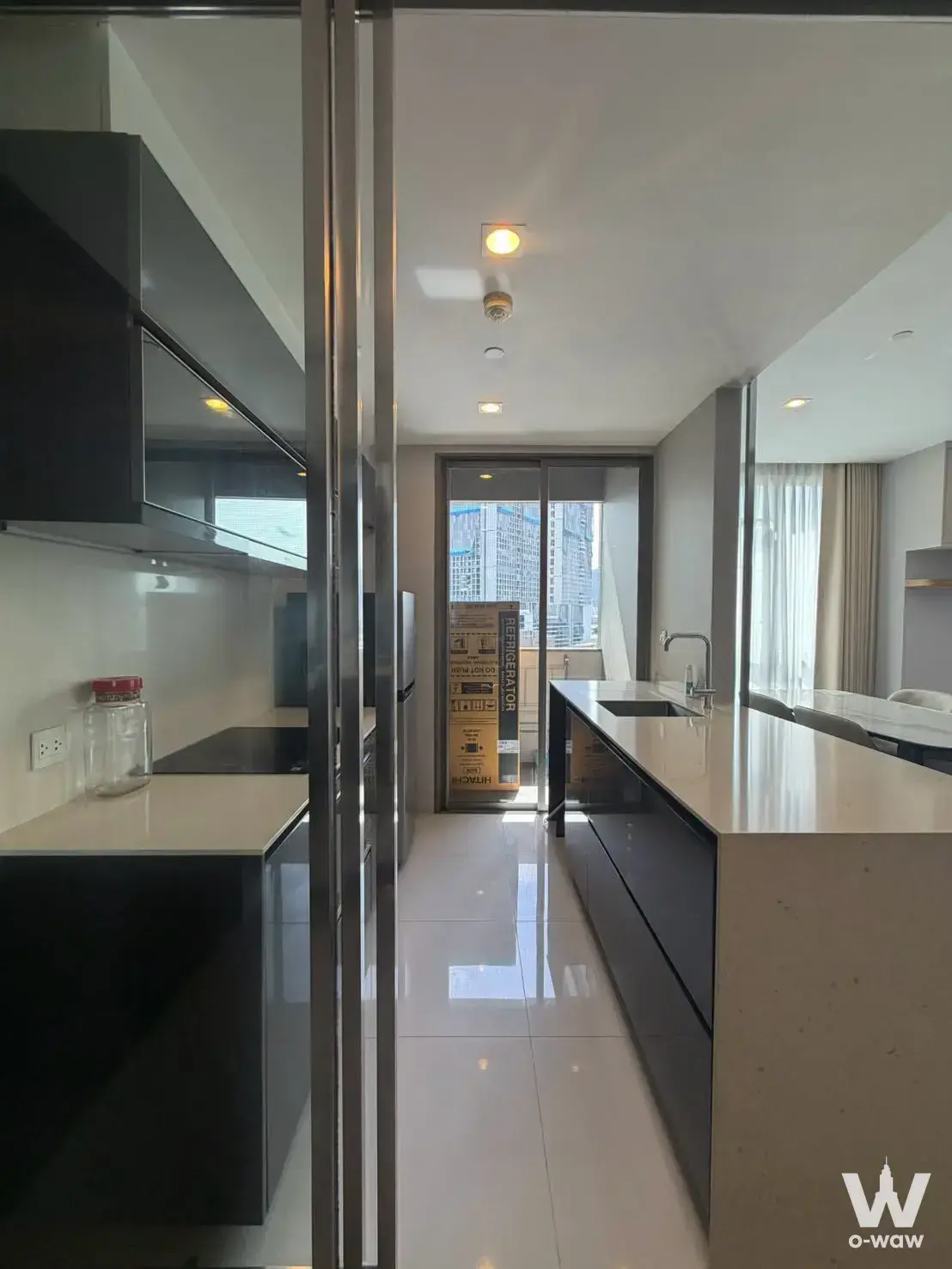 Modern kitchen in a 2-bed condo for rent at The Room Rama 4 featuring black cabinets, white quartz counters, and a city view