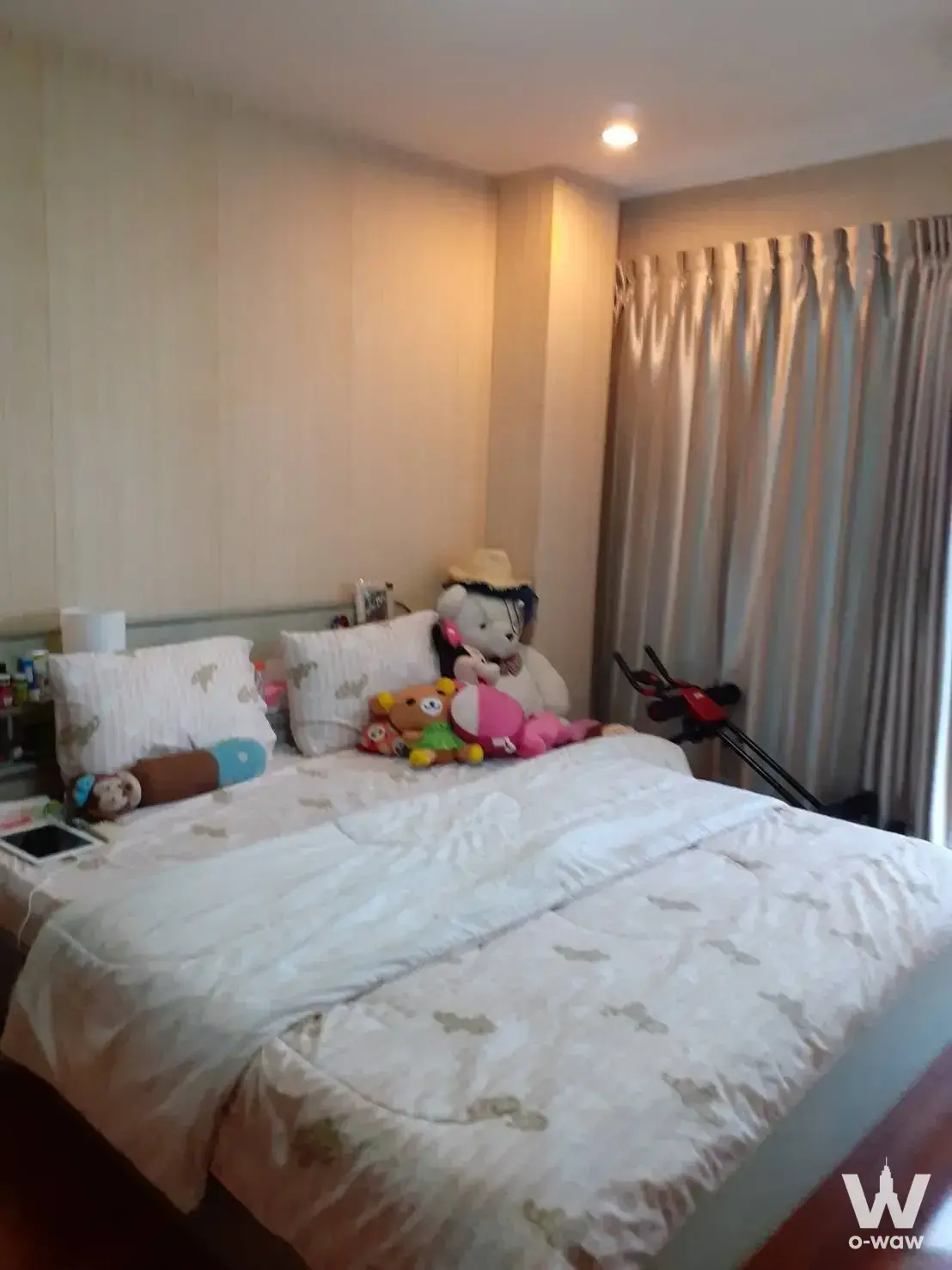 Modern 1-bed condo bedroom in NS Towers featuring a queen bed, plush toys, and exercise bike