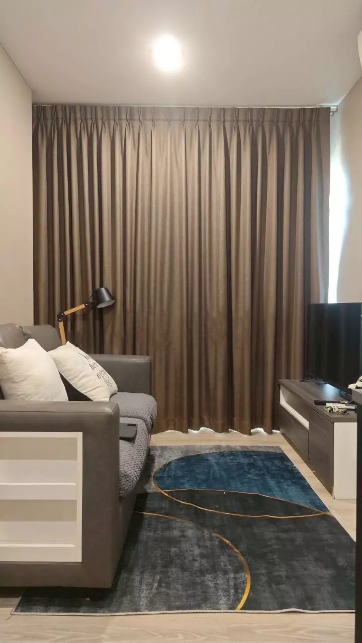 1-bed condo for rent in Chewathai Phetkasem 27 with dark grey sofa and navy geometric rug