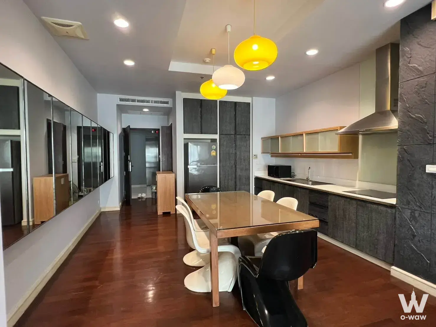 Open-plan dining area in a Noble Ora 2-bed condo with dark wood floors and pendant lighting over the table