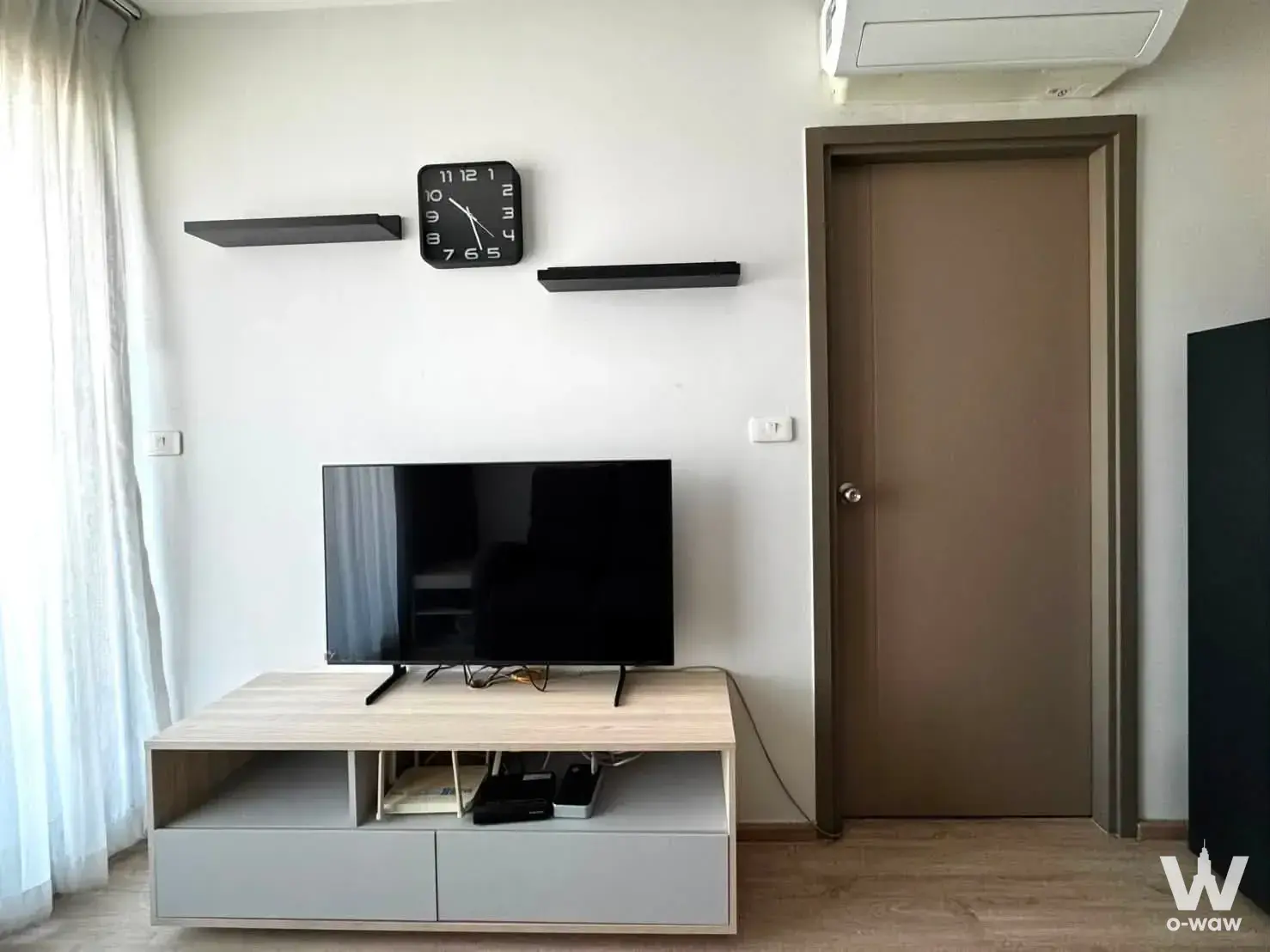 Minimalist 1-bed condo for sale in Ideo O2 Building B with light wood flooring, black shelves, and neutral decor