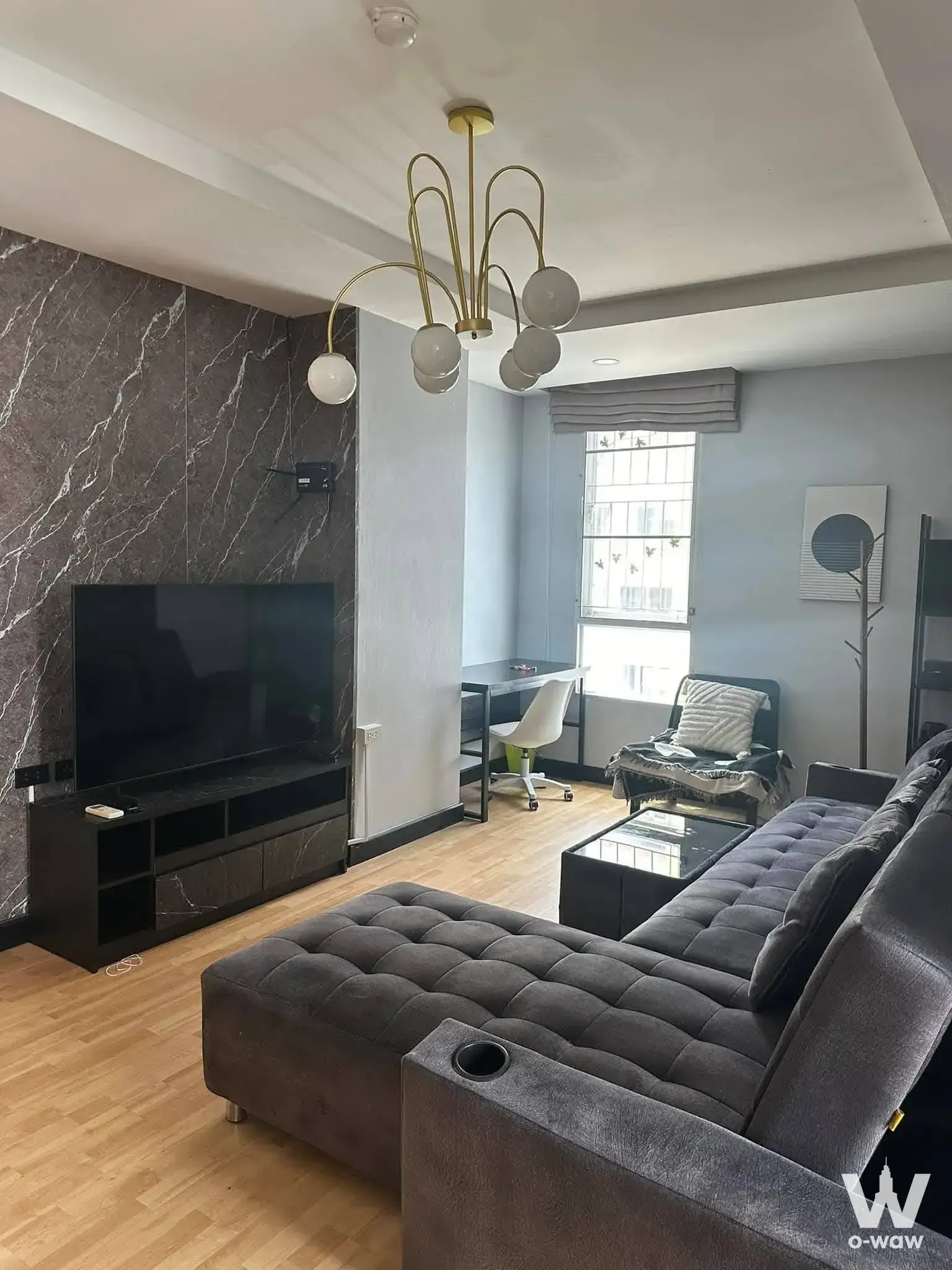 Modern 1-bed condo living room in Condo Ratchada City18 with dark marble TV wall and gold chandelier
