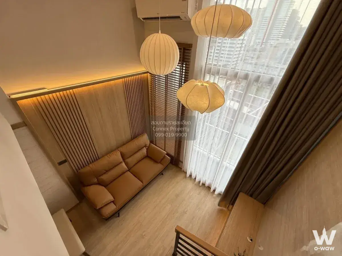 Living room in a 1-bed Culture Chula rental with tan leather sofa and wood slat feature wall