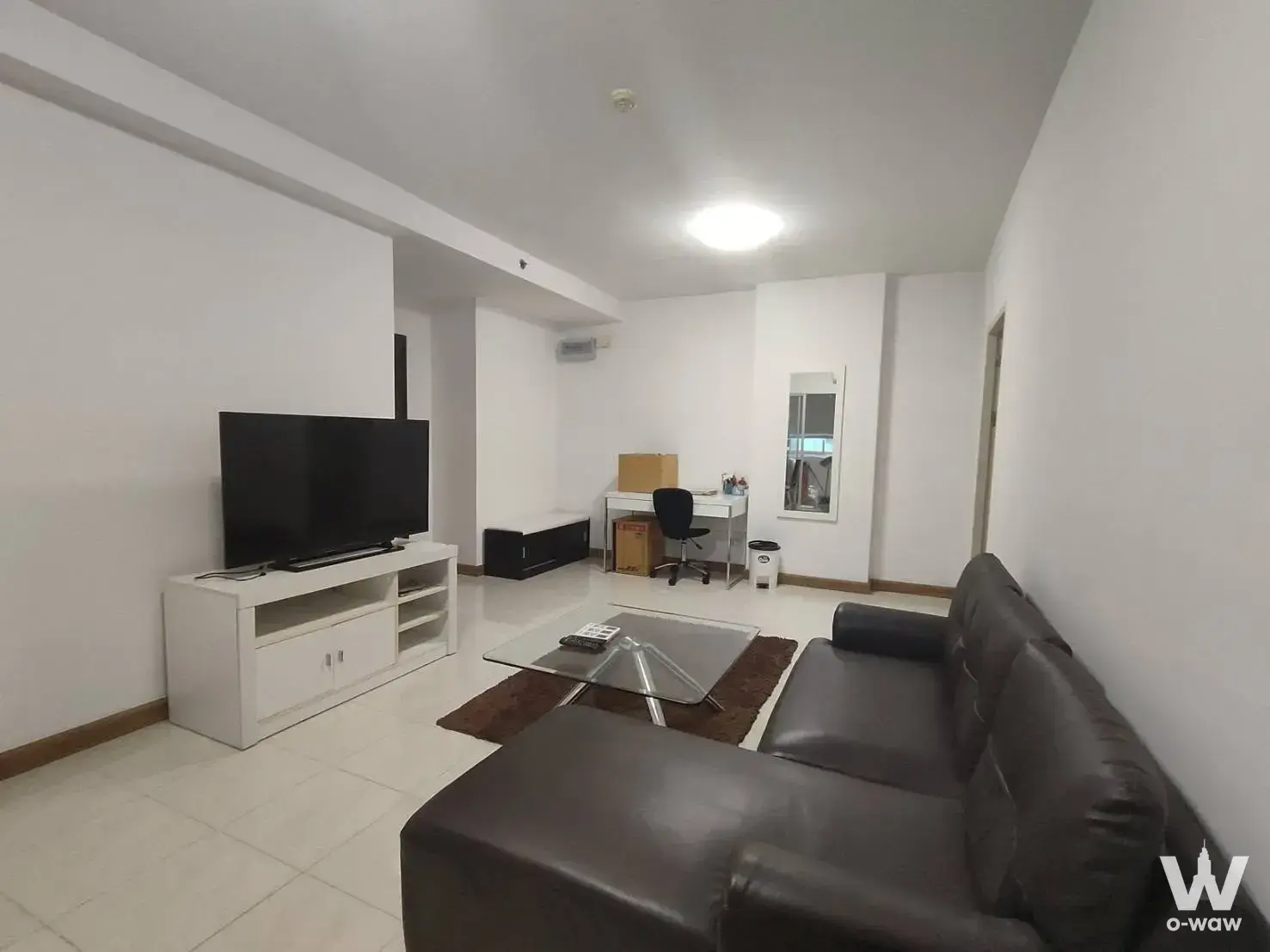 Living room in Supalai Park Ekkamai with dark brown leather sofa and white TV console