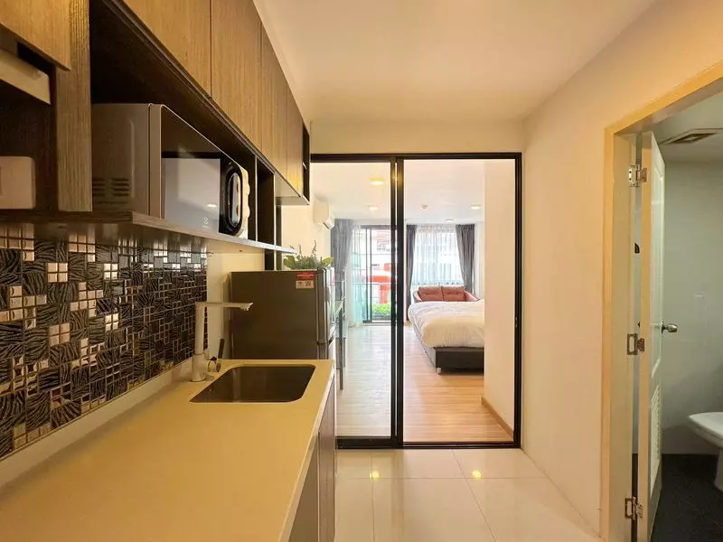 Open-plan kitchenette in Chateau In Town Pinklao featuring mosaic backsplash and view into bedroom