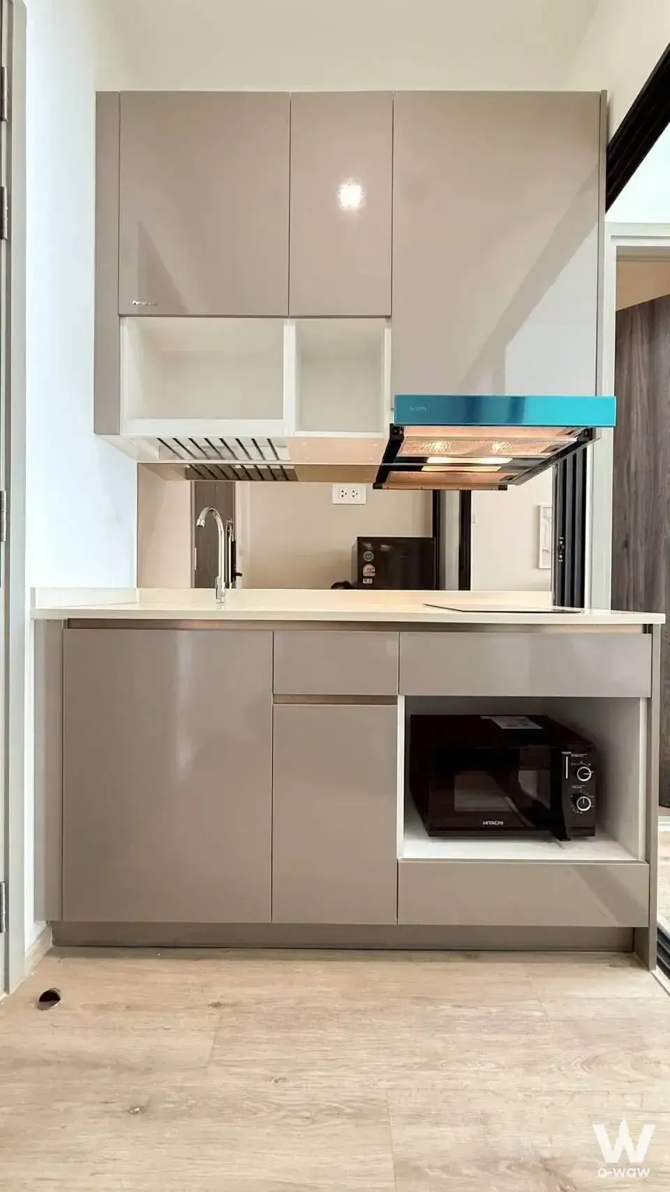 Compact kitchen with taupe cabinets and teal range hood in this fully furnished 1-bed condo rental
