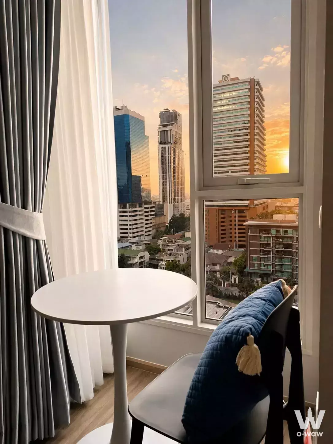 Window seating nook in a 1-bed Culture Thonglor condo featuring floor-to-ceiling glass and a sunset city view