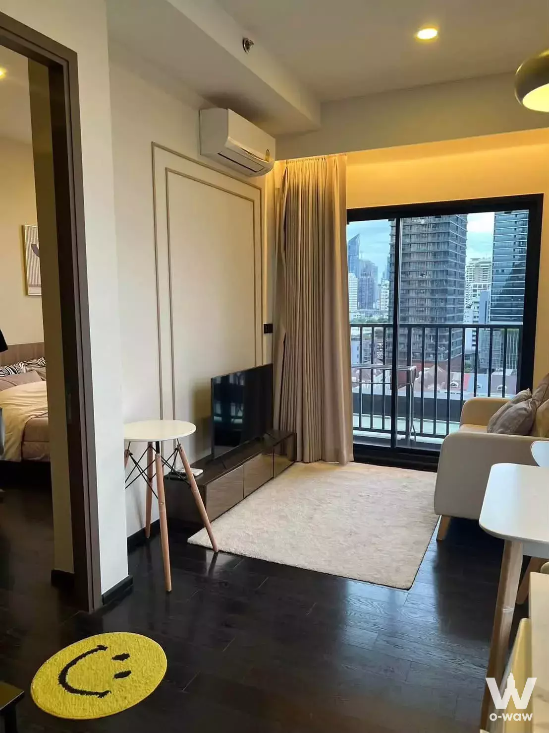 Living room with city view and beige sofa in this Park Origin Thonglor 1-bed condo for rent