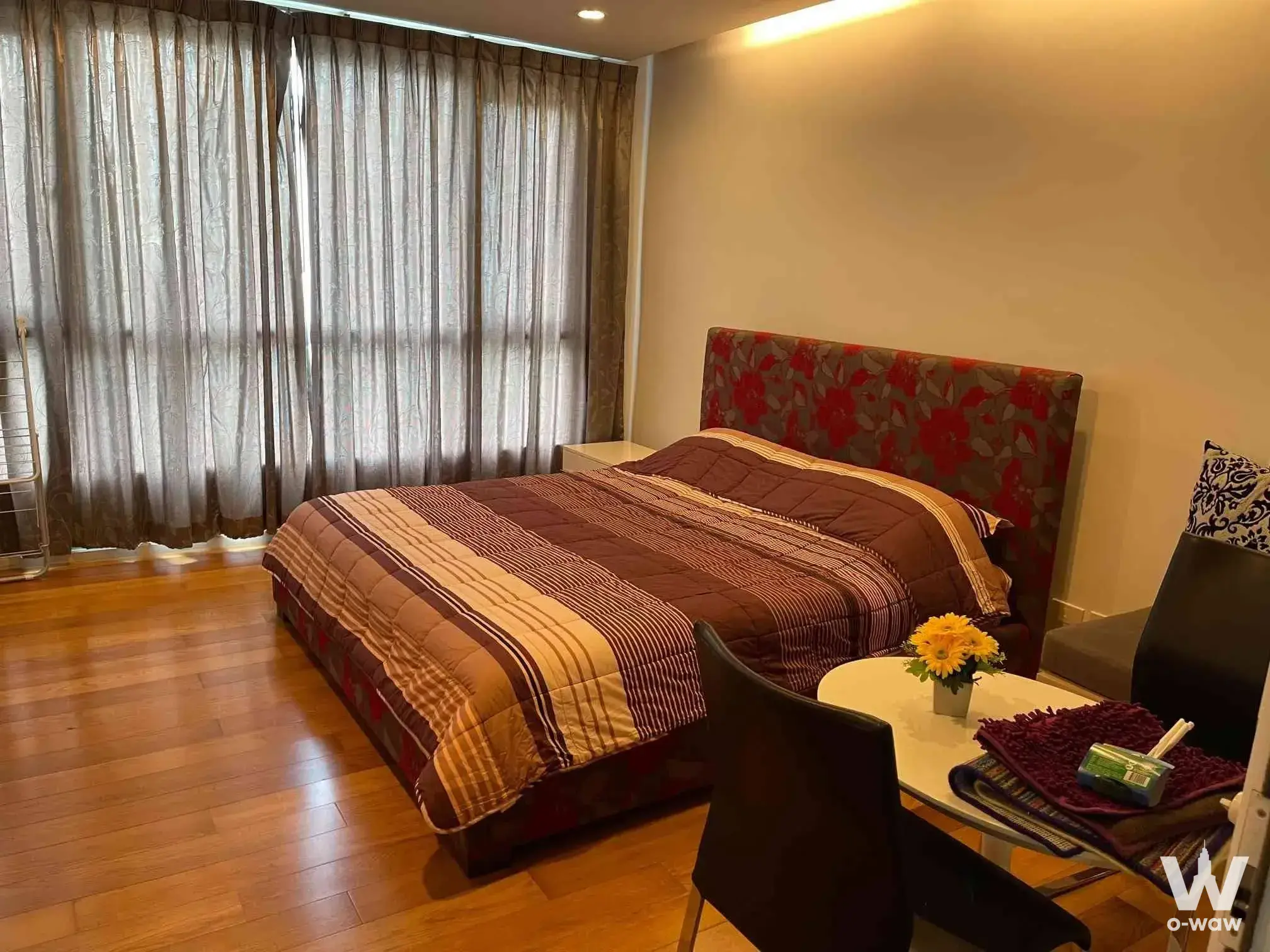 1-bed condo for sale in 15 Sukhumvit Residences bedroom with floral headboard and wood-look plank flooring
