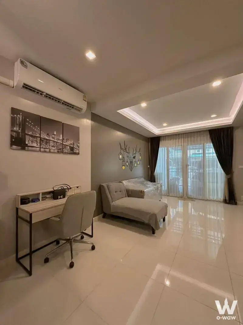Townhouse living room in Bless Town Srinakarin-Namthong with white tile floors, grey chaise lounge, and city skyline canvas