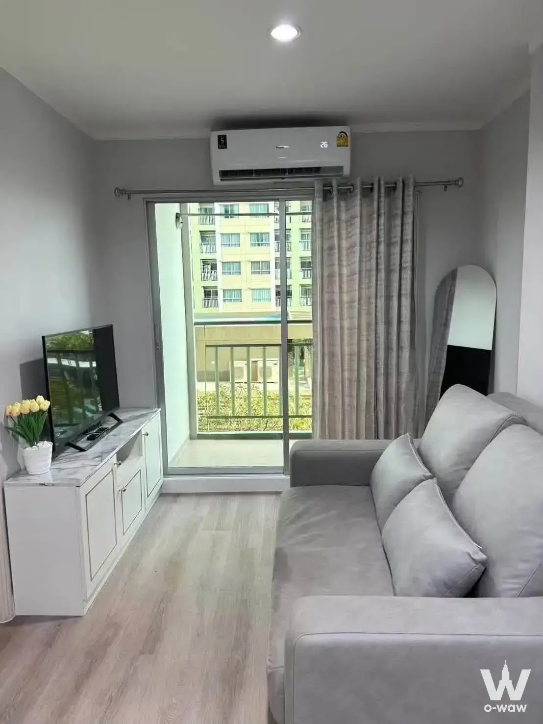Bright living room in Lumpini Park Rama 9 condo with grey sofa and balcony view