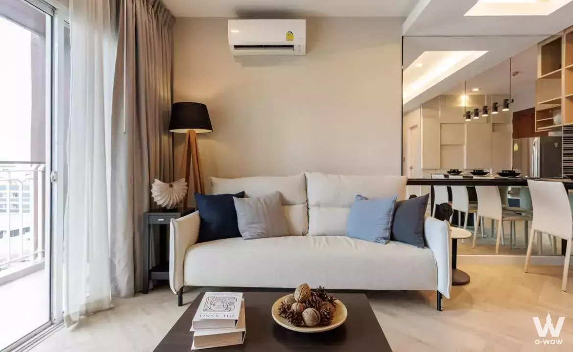 Cream leather sofa and navy pillows in the open-plan living room of a The Complete Ratchaprarop rental unit