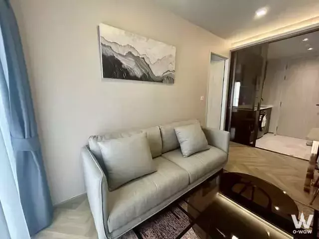 Living room in Chapter Thonglor 25 with leather sofa, wood coffee table, and abstract mountain art