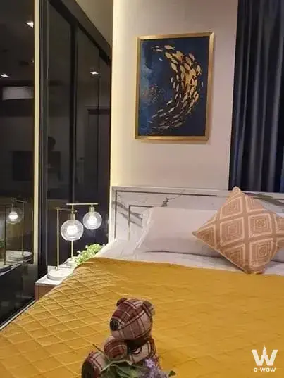 Queen bed with mustard throw and gold fish art in a bedroom of this 2-bed condo for rent at Life Sukhumvit 62