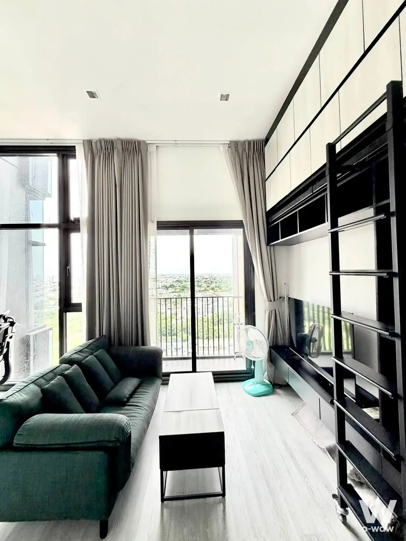 1-bed condo for rent in THE LINE Sukhumvit 71 living room with dark green sofa and balcony access