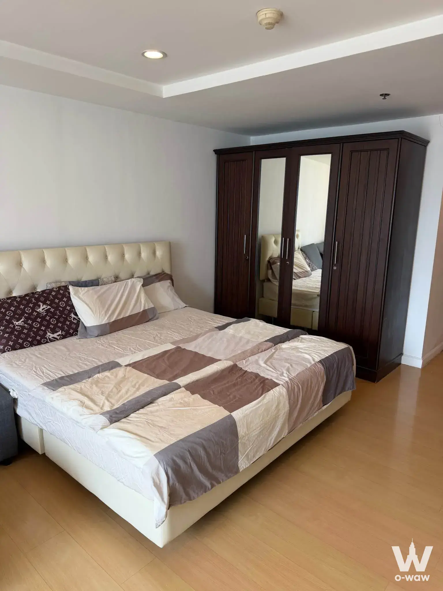 This 1-bed condo at The Trendy Condominium has a bedroom with a queen bed and dark wood mirrored wardrobe