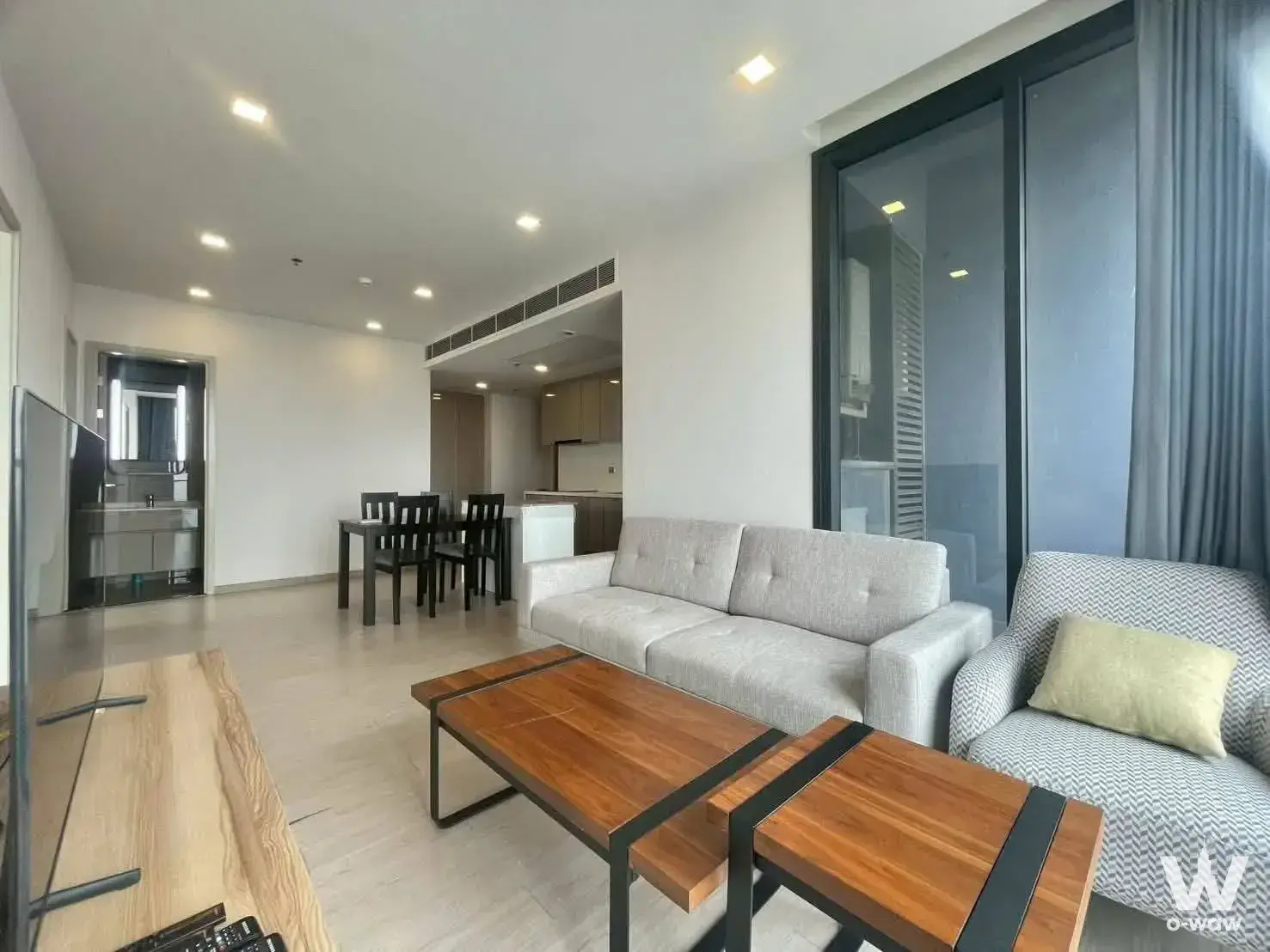 Open-plan living area in One9Five Asoke with grey sofa and dining set near kitchen