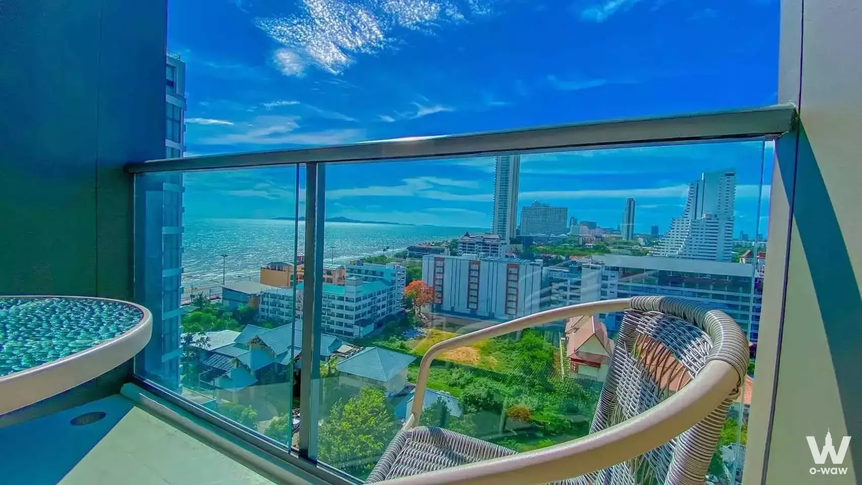 Wicker armchair on a glass-railed balcony overlooking the ocean at AERAS Beachfront Jomtien Pattaya