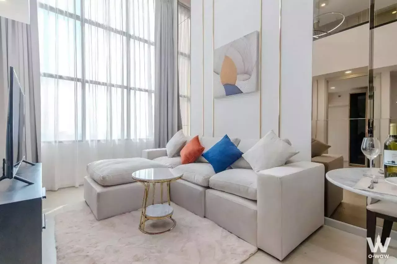 Living room in a KnightsBridge Prime Sathon 2-bed condo with L-shaped sofa and floor-to-ceiling windows
